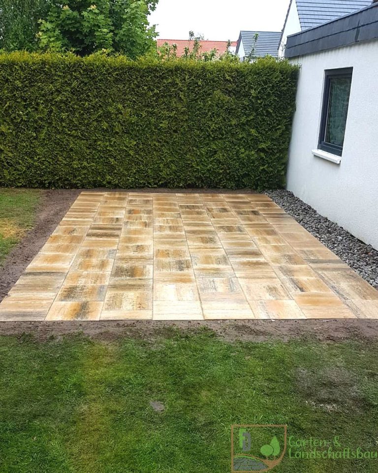 Neu verlegte Terrasse mit Rasen und Hecke