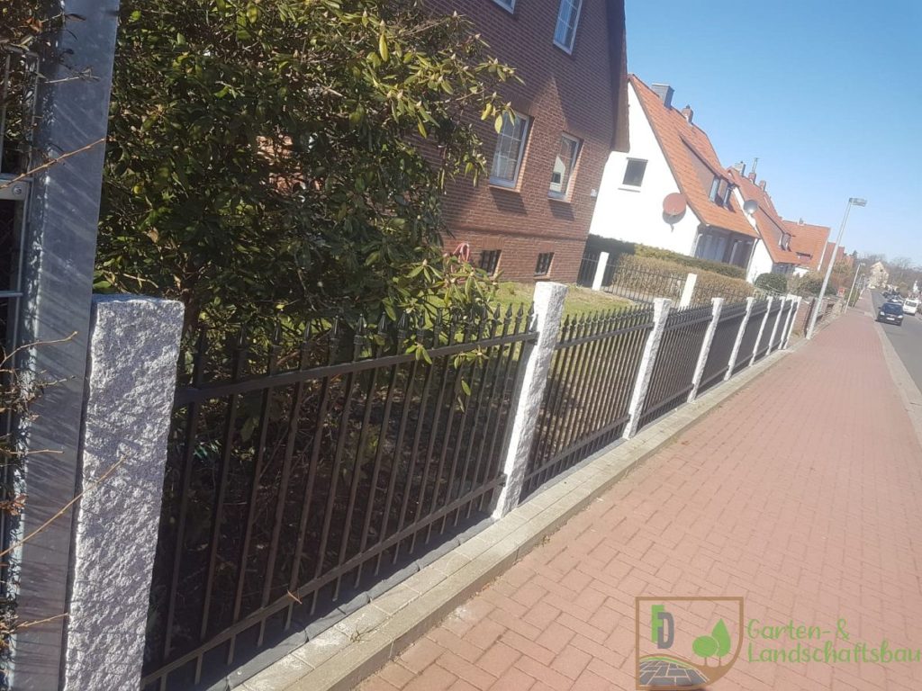Metallzaun mit Granitsäulen entlang des Gehwegs