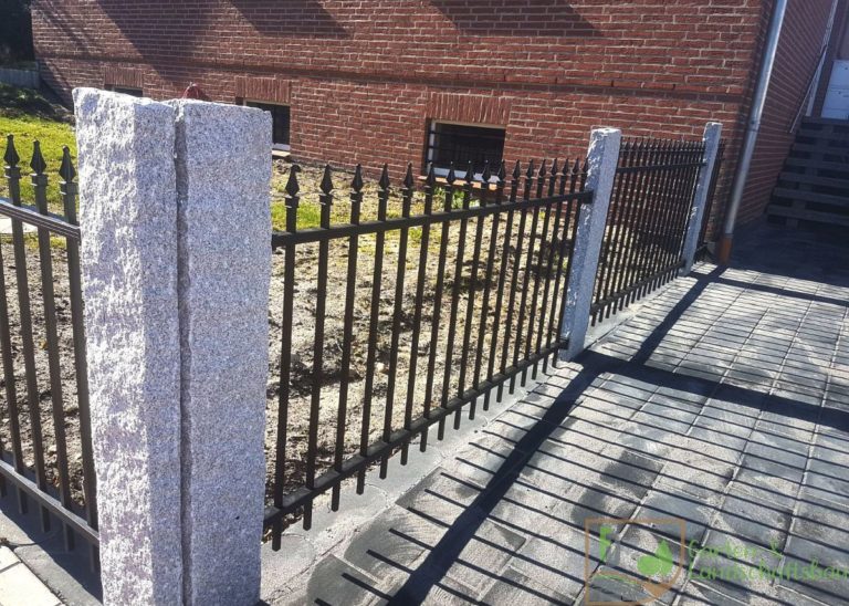 Stabzaun mit Granitpfosten an gepflasterter Fläche