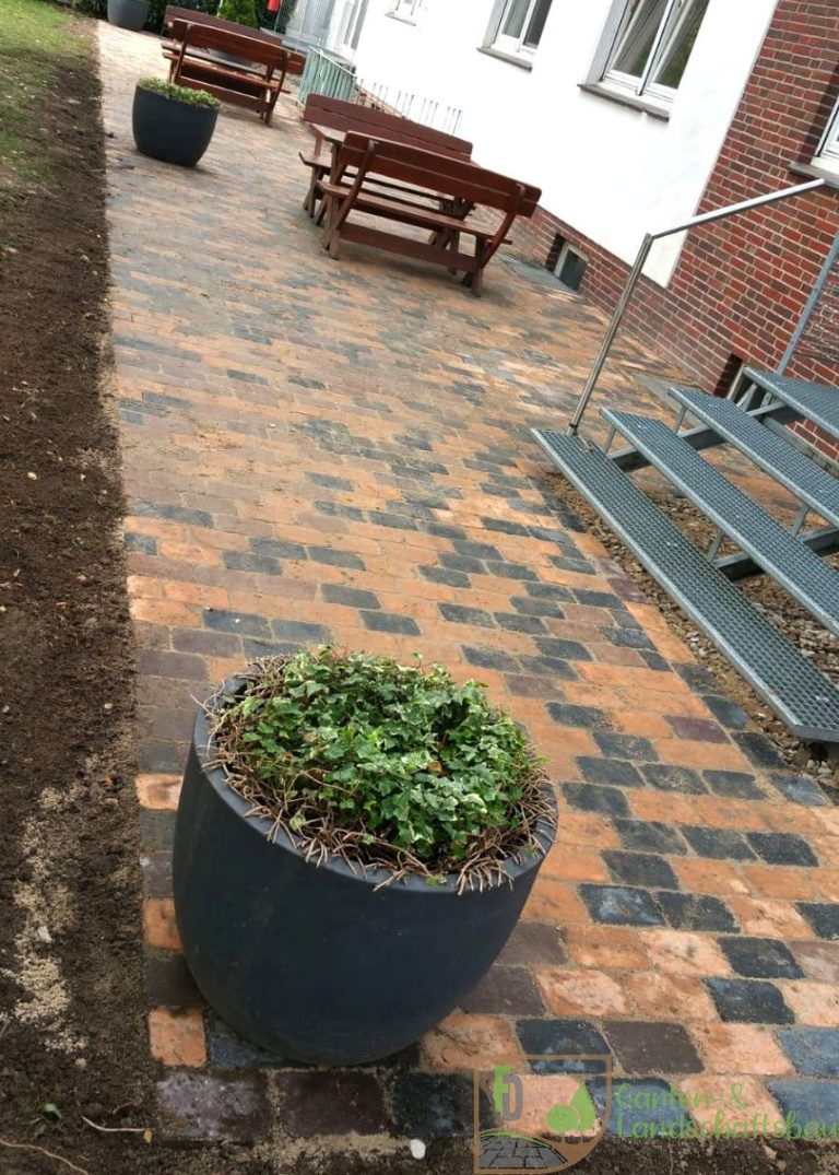 Gepflasterte Terrasse mit Treppe und Pflanzkübel